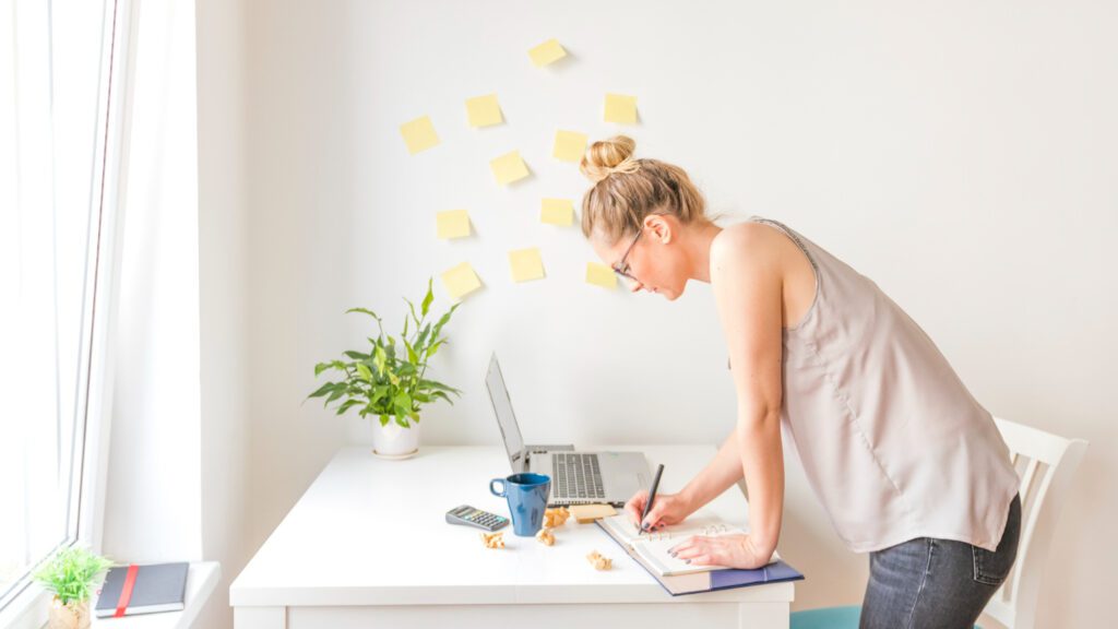 Person focused on completing tasks at a desk with planner, laptop, and coffee, representing productivity and overcoming procrastination