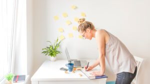 How to beat laziness and boost your productivity every day Person focused on completing tasks at a desk with planner, laptop, and coffee, representing productivity and overcoming procrastination